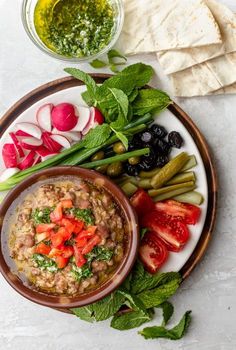 a white plate topped with beans and veggies next to pita bread