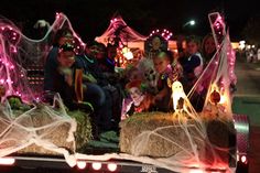 people sitting on hay bales in the back of a truck decorated with halloween decorations