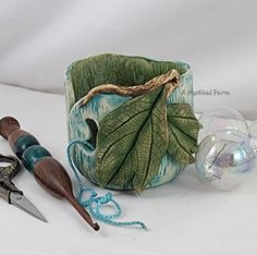 a cup that has some kind of leaf on it next to scissors and other items