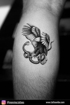 a man's arm with an eagle and snake tattoo on the left side of his leg