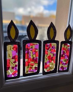 three candles made out of stained glass sitting on a window sill