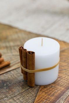 cinnamon sticks wrapped around a white candle on a wooden table