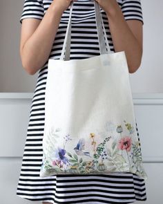 a woman holding a white bag with flowers on it