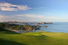 a golf course overlooking the ocean and small island in the distance on a sunny day