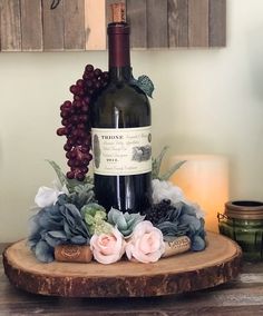 a bottle of wine sitting on top of a wooden table next to flowers and candles