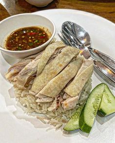 a white plate topped with rice and meat next to a bowl of soup