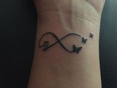 a small tattoo on the wrist of a woman with butterflies around her neck and an infinite symbol