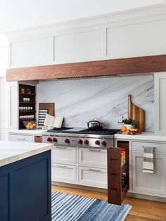 a kitchen with white cabinets and marble counter tops, blue rugs on the floor