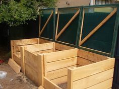 three wooden planters sitting in front of a green fence and building with trees behind them