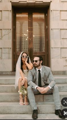 a bride and groom sitting on steps in front of a building