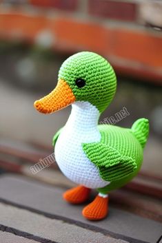 a crocheted duck sitting on top of a wooden bench