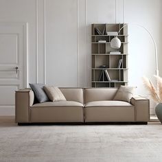 a living room with a couch, book shelf and vases on the floor in front of it