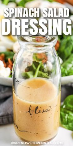 a glass jar filled with dressing next to a salad on a plate and the words spinach salad dressing