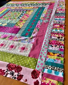 a colorful quilt is laying on top of a wooden table with polka dots and flowers