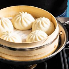 steamed dumplings in a wooden bowl on top of an electric stove