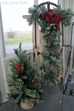 two christmas wreaths sitting next to each other in front of a window