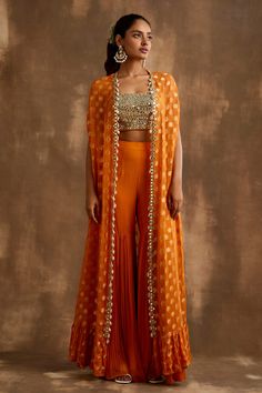 Shop for these amazing collections of Orange Georgette Embroidered Mirrorwork Floral Pattern Gharara Set For Women by Niamh By Kriti online at Aza Fashions. Cape Indian Outfit, Orange Indo Western Outfits, Orange Traditional Outfits, Indian Cape Outfits, Festive Fitted Anarkali Set With Cape Sleeves, Festive Floor-length Sets With Gota Work, Chanderi Lehenga With Zari Work And Cape Sleeves, Floor-length Gota Work Sharara For Festive Occasions, Navratri Palazzo Set With Zari Work And Cape Sleeves