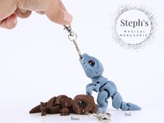 a tiny blue alien keychain being held by someone's hand over chocolate pieces