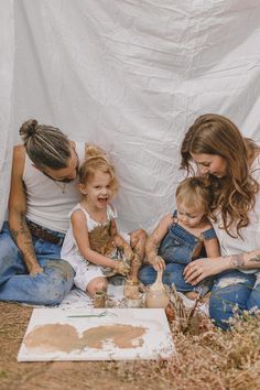 a woman and two children are sitting on the ground