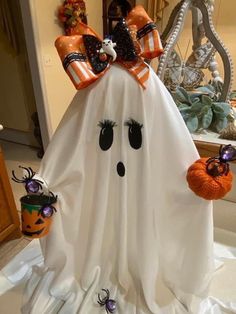 a white ghost with two pumpkins on it's head and some decorations in the background