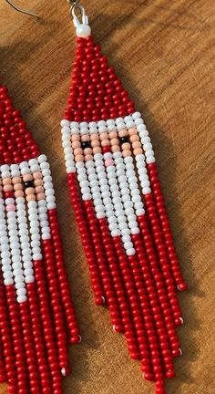 red and white beaded earrings with santa face on them, sitting on a wooden surface