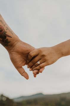 two people holding hands with tattoos on their arms and one is holding the other's hand