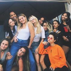 a group of young women posing for a photo in front of a tent with their arms around each other