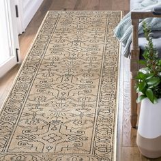 a beige rug with black and white designs on the floor next to a potted plant