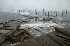 a bunch of wooden planks that are in the water and some waves crashing over them