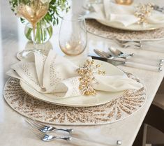 the table is set with white and gold plates, silverware, and napkins