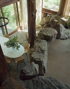 a table and chairs in a room with large rocks on the floor next to it