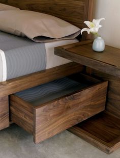 a bed with a wooden headboard and night stand next to a small end table