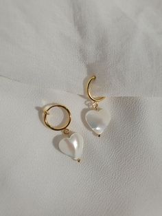 These dainty earrings are made with freshwater shell heart pearls and gold or platinum plated huggie hoops. This plating protects against wear and tear, tarnishing, and light contact with substances such as water. Closures: * Pierced gold hoops are hypoallergenic and nickel free (18 karat gold plated). * Pierced silver hoops are hypoallergenic and nickel free (platinum plated). * Clip on gold hoops are hypoallergenic and nickel free (18 karat gold plated). * Clip on silver hoops are hypoallergen White Heart-shaped Pearl Charm Earrings, White Dainty Earrings With Heart Charm, Heart Charm Pearl Earrings As A Gift, Heart Charm Pearl Earrings For Gift, White Hoop Earrings With Heart Charm, Dainty Heart-shaped Pearl Drop Earrings, White Hoop Earrings With Heart Charm For Gift, White Heart-shaped Earrings With Pearl Charm, Heart-shaped Pearl Charm Earrings As Gift