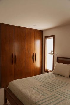 a bed sitting in a bedroom next to a tall wooden cabinet with two lamps on top of it