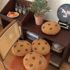 four stuffed cookies sitting on top of a brown chair next to a table with an alarm clock