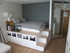 a bed sitting on top of a wooden floor next to a white shelf filled with pictures