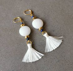 Elegant white and gold earrings with a hint of contrasting navy - perfect for adding a sophistcated finishing touch to your outfit on any occasion. These gorgeous handmade drop earrings feature white agate coins set between two flying saucer shaped gold beads, topped with blue lapis lazuli. Playfully hanging below the semi precious stones is a silky white silk tassel. The earrings close with a lever back ear wire. All metal is gold-plated. These navy and white dangle earrings form part of of my White Tassel Earrings With Latkans As Gift, White Tassel Earrings With Latkans For Gift, White Dangle Tassel Earrings With Latkans, Elegant White Tassel Earrings For Pierced Ears, White Drop Earrings With Latkans, White Latkans Drop Earrings, White Latkan Drop Earrings, White Tassel Earrings, Blue Gemstone Bracelet