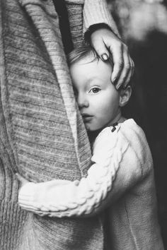 black and white photograph of a woman holding a child's arm while they both wear sweaters