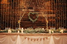 the table is set up with candles and greenery for an elegant wedding reception in front of a brick wall