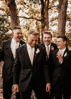 a group of men standing next to each other in front of some trees and leaves