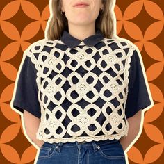 a woman wearing a crochet top and jeans standing in front of an orange background