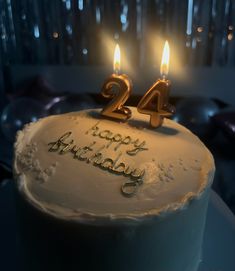 a birthday cake with two candles on it and the number twenty four written in gold