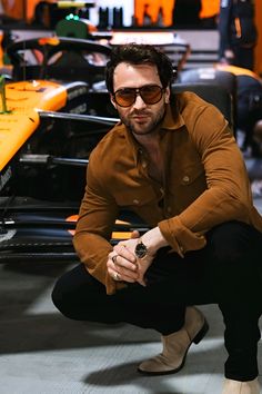 a man sitting on the ground in front of a race track with his hand on his knee