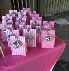 pink and white striped bags with disco balls on them sitting on a table in front of a window