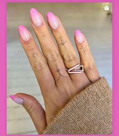 a woman's hand with pink nail polish and an arrow tattoo on her ring