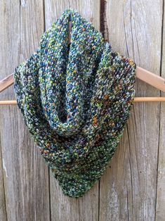 a close up of a knitted scarf on a wooden hanger with clothes pins