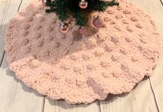 a pink crocheted rug with ornaments on it and a christmas tree in the middle