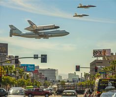 a space shuttle is flying over cars on the street in front of buildings and traffic lights