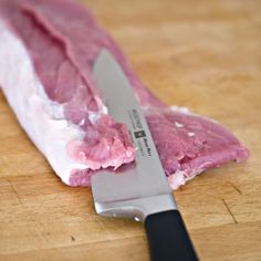 a piece of raw meat on a cutting board with a knife