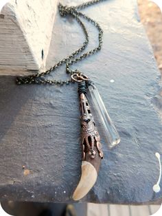 a necklace with a long horn on it and a chain hanging from the end that is attached to an old book